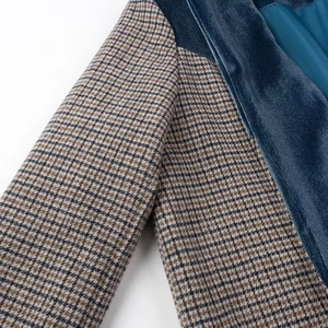 Dettaglio della trama pied-de-poule e delle cuciture in velluto blu sul cappotto alla moda