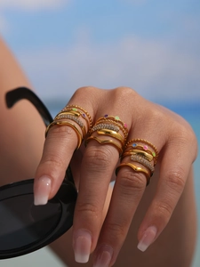 Close-up of gold stainless steel rings with 5A zircon and colorful enamel on a model hand