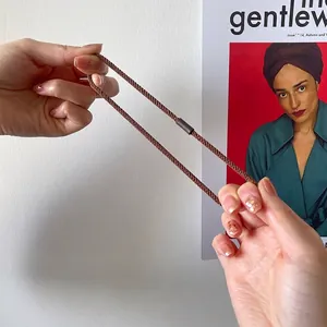 Brown woven houndstooth elastic hair tie being stretched to show high elasticity