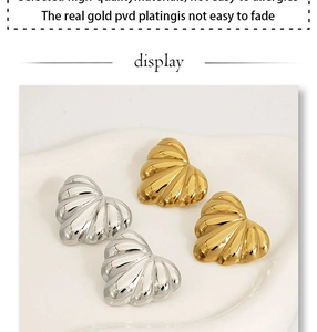 Macro view of PVD gold plated heart earrings with textured radiating wave patterns