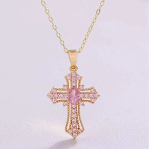 Macro shot of gold cross necklace with pink zircon oval stone and pavé crystal detail