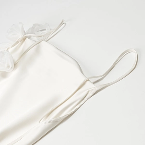 Close-up of white satin backless dress featuring a delicate 3D floral gauze ornament