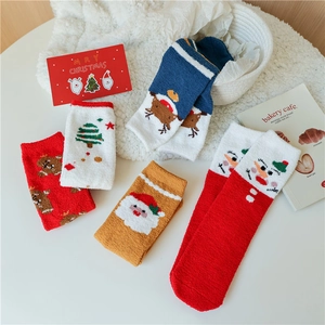 Gros plan de chaussettes de Noël en polaire corail avec broderies sur table blanche