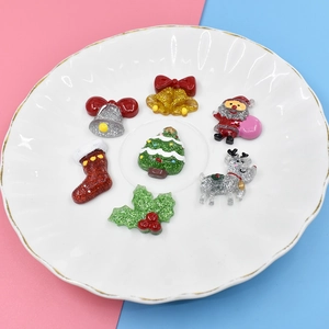 Macro shot of colorful glitter resin Christmas charms including Santa and tree in a white dish