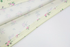 Close-up of floral fabric detail with pink flowers on yellow base and neat overlock stitching