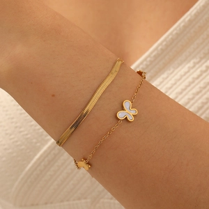 Layered gold plated stainless steel bracelet set with butterfly charm on a female wrist