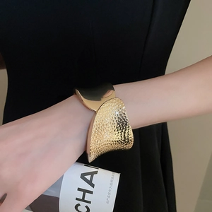 Close-up of golden irregular open bangle with contrasting hammered and polished textures