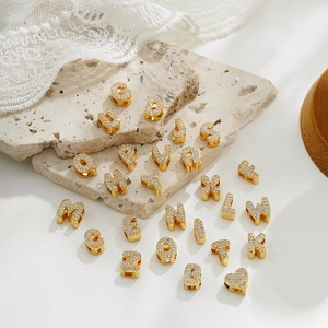 Detailed view of 18k gold plated alphabet and heart pendants with zircon inlay stones