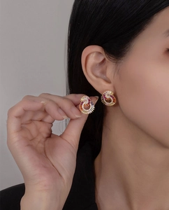 Detail of colorful gradient zircon stud earrings in gold-tone spiral design on model