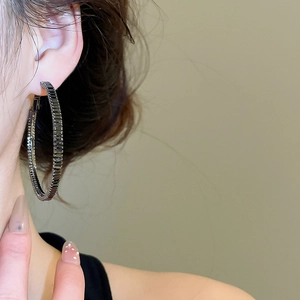 Close-up of large round hoop earring with black square zircons worn by a model