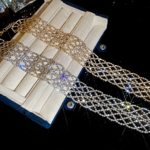 Gros plan de colliers ras de cou en strass or et argent dans un écrin bleu