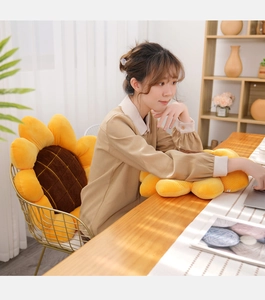 Cozy sunflower cushion on gold chair with a woman using a laptop in a bright home office
