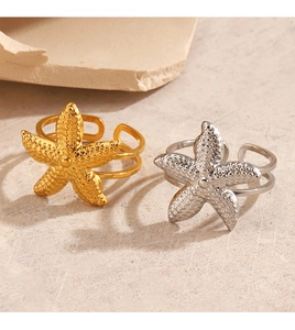 Close-up of gold and silver starfish rings on a textured rock for a beach holiday vibe