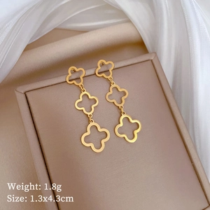 Golden clover tassel drop earrings displayed on a luxury silk and jewelry box setting