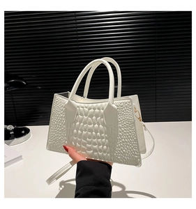 Detailansicht der weißen Krokoprägung und des Griffs einer eleganten Damen-Handtasche aus PU