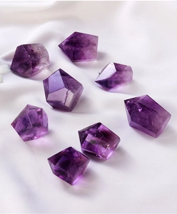 Top view of natural purple amethyst hex prisms on white silk for energy healing decor
