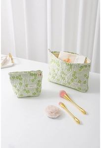 Detail of light green floral embossed makeup bags with golden zippers and fabric roses