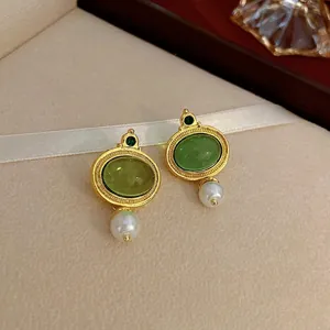Boucles d'oreilles vintage dorées avec pierres vert émeraude et perles sur soie blanche