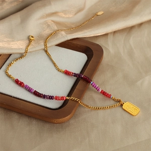 Golden necklace with a rectangular pendant and colorful agate beads on silk fabric