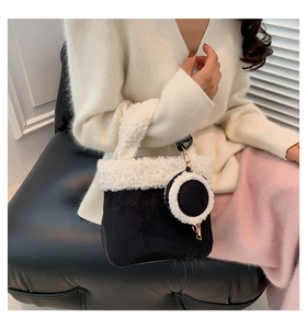 Detail of suede bucket bag with white faux shearling trim and round coin purse charm