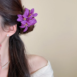 Detail of purple fabric flower hair pin with dewdrop accents on model's hair