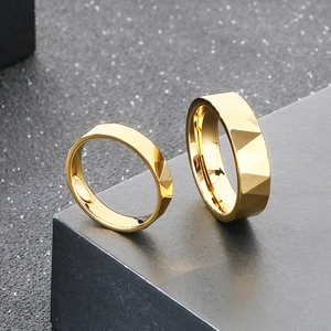 Dettaglio di anelli in acciaio al tungsteno dorato con sfaccettature geometriche lucide a V