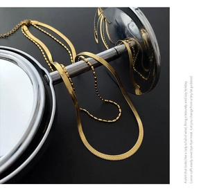 Detail of double-layer gold snake and bead chain necklace with lobster clasp and extender