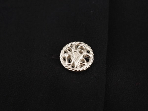Detail shot of the textured black fabric with a vintage silver hollow-out metal button