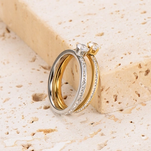 Polished six-claw stainless steel ring set with zircon stones on travertine background