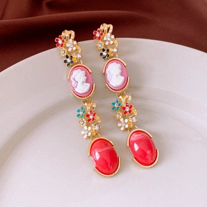 Détail de boucles d'oreilles style cour française avec camée et pierres rouges