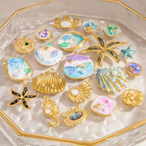 Marine life charms set in gold with colorful enamel and pearls on glass tray