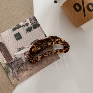 Detail of Creation France logo on large acetate hair claw with amber tortoise pattern