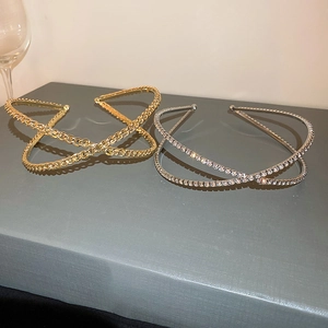 Detail of gold chain and silver rhinestone criss-cross headbands on a textured surface