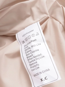 Macro shot of 100% polyester wash care label with cleaning symbols on women's faux fur coat
