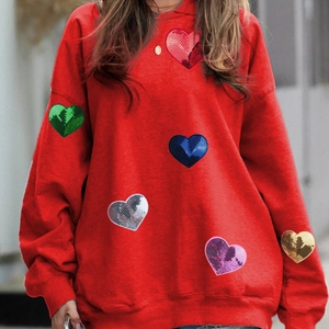 Detail of colorful sequin heart patches on red oversized hoodie for DIY decoration
