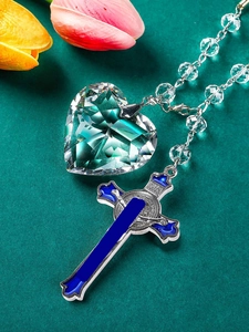 Detailed view of car rosary with crystal heart pendant and blue enamel cross on fabric