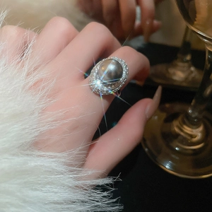 Close-up of a luxury silver ring featuring a large grey pearl surrounded by sparkling zircons