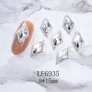 Set de gemas de rombo para uñas con marco de metal plateado y cristales sobre mármol