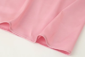 Dettaglio dell'orlo in raso rosa che mostra la cucitura fine e la trama lussuosa del tessuto