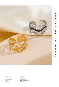 Detail of wave-shaped enamel rings in gold and silver on soft silk fabric background