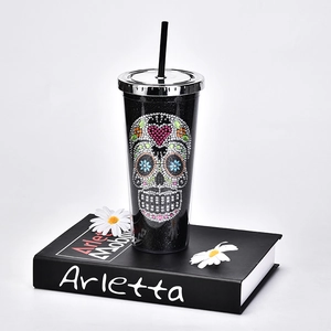 Detailed view of black straw cup featuring a colorful rhinestone skull on a book background
