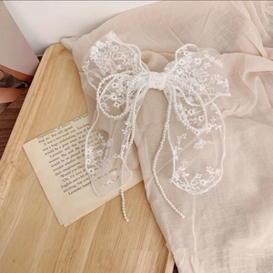 Detailed view of white lace bow hair clip with floral embroidery and pearl beads decoration