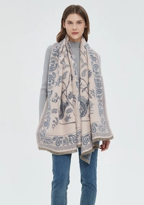 Detail of beige and blue paisley scarf featuring soft fabric and fringe edges on model