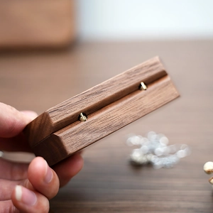 Close-up of metal hinges and natural walnut wood texture on a mini travel jewelry box