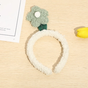 Close-up of white plush tulip headband with green flower on spring on wooden desk
