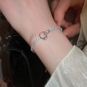 Close-up of silver zircon tennis bracelet with a creative mini ring charm pendant