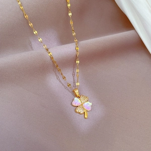 Macro detail of gold four-leaf clover necklace with iridescent inlay and cubic zirconia