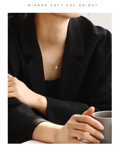 Silver chain necklace with an oval clear stone pendant worn on a female model