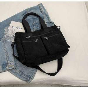 Close-up of black corduroy tote bag with dual front pockets and detachable shoulder strap