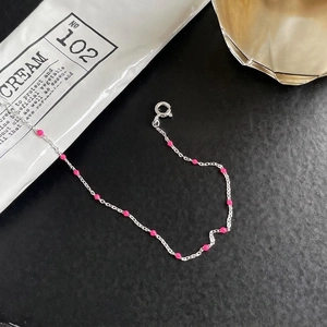 Minimalist 925 sterling silver beaded bracelet with pink enamel drops on a black background